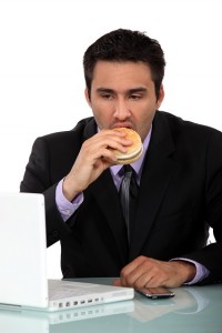 businessman-eating-hamburger-at-desk
